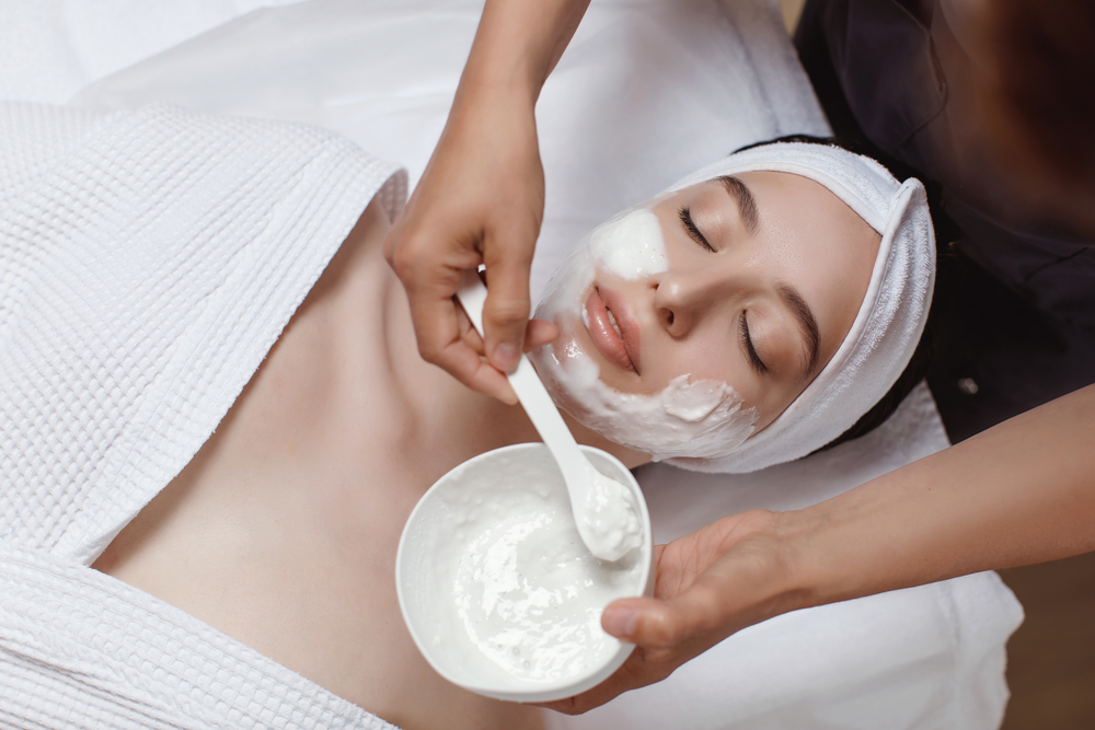 Eine Frau während einer Basic Gesichtsbehandlung mit aufgetragener Pflegemaske in einer ästhetischen Praxis Medicare aesthetics